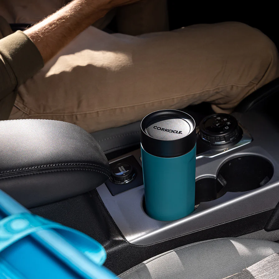 corcickle commuter cup in the cupholder of a car with a man driving