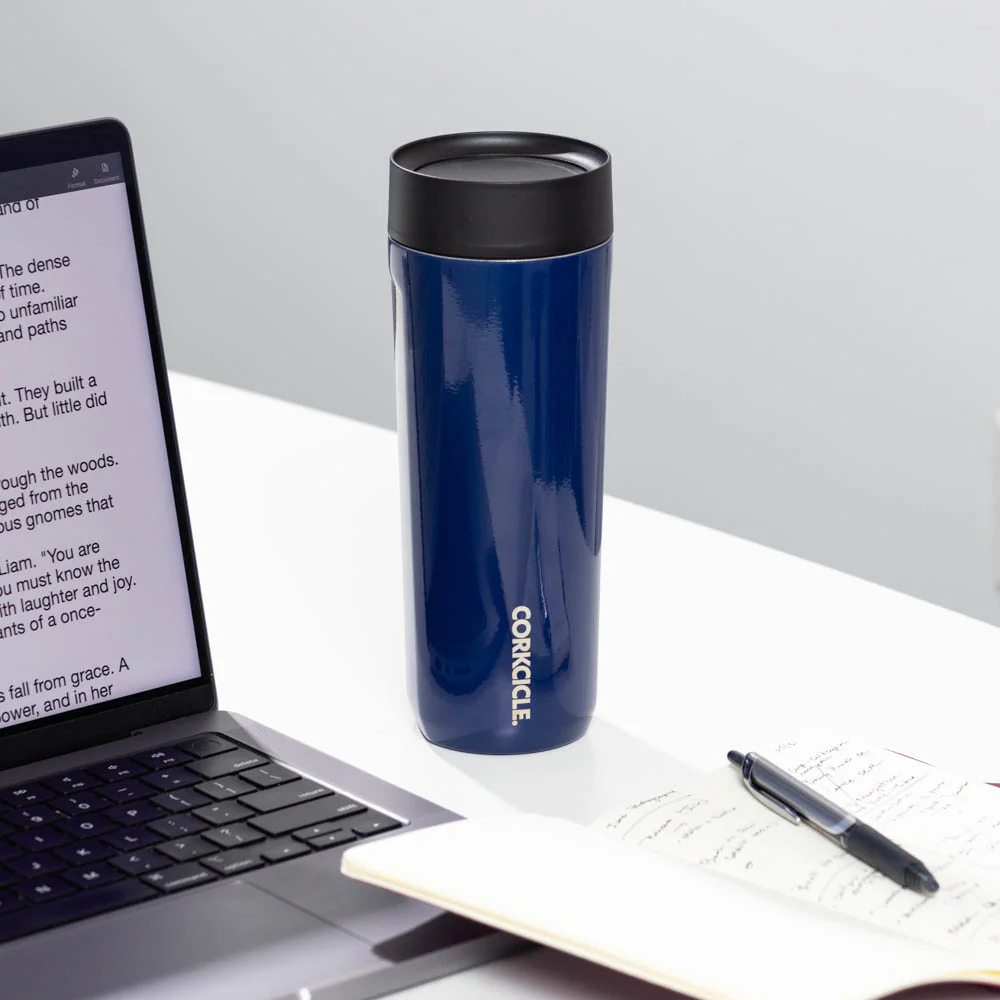 corkcicle commuter cup sitting on a desk next to a journal, pen, and laptop